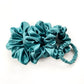 Set of teal blue pure mulberry silk satin scrunchies and hair ties on a white background