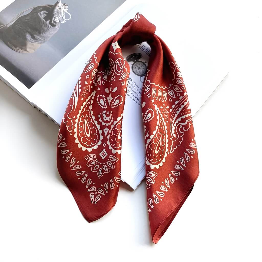 terracotta red mulberry silk square scarf with white paisley patterns on a magazine