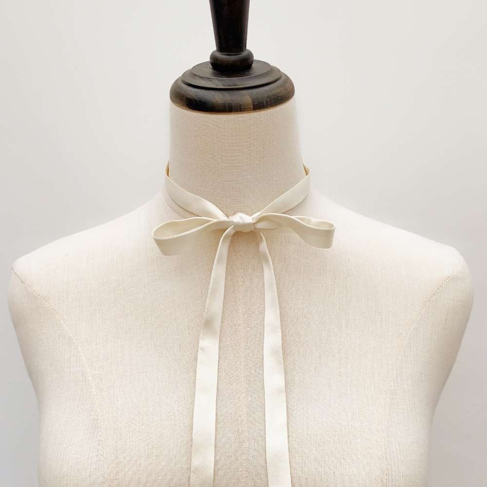 Mannequin wearing a ultra skinny ivory cream-colored mulberry silk neck tie against a plain background