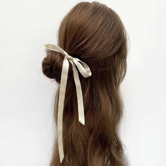 Brown hair styled in an updo with a ivory cream mulberry silk ribbon against a white background