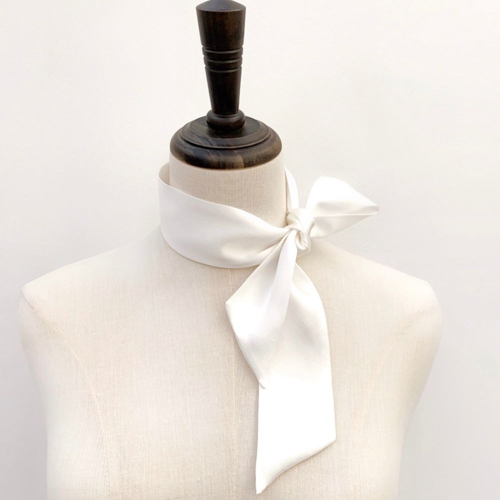 A white mulberry silk satin skinny scarf tied around mannequin's neck