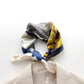 Colourful mulberry silk neckerchief with abstract patterns draped over a white surface