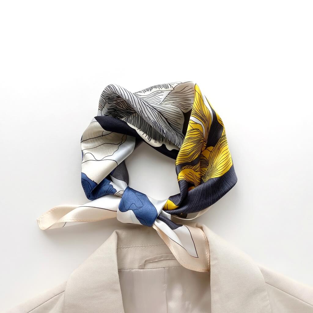 Colourful mulberry silk neckerchief with abstract patterns draped over a white surface