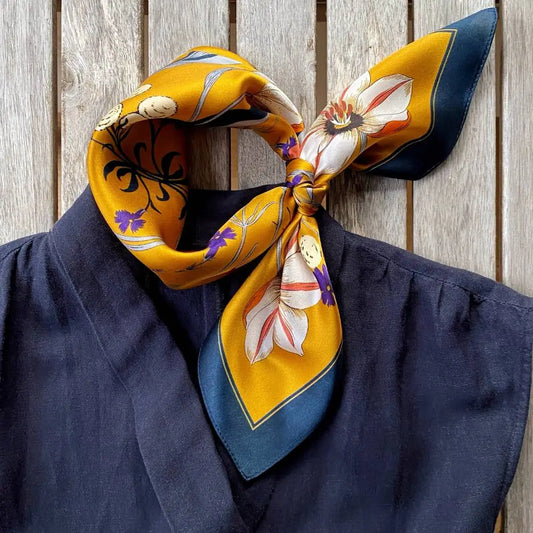 Colorful floral scarf draped over a navy blue garment against a wooden background
