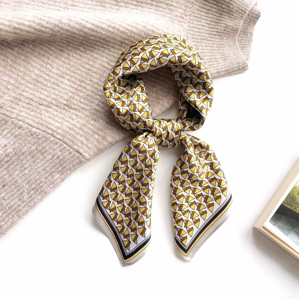 yellow brown geometric patterned mulberry silk bandana scarf on a textured surface