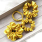 Four yellow silk scrunchies on a wooden surface