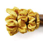 yellow silk scrunchies and hair tie on a wooden block with a white background