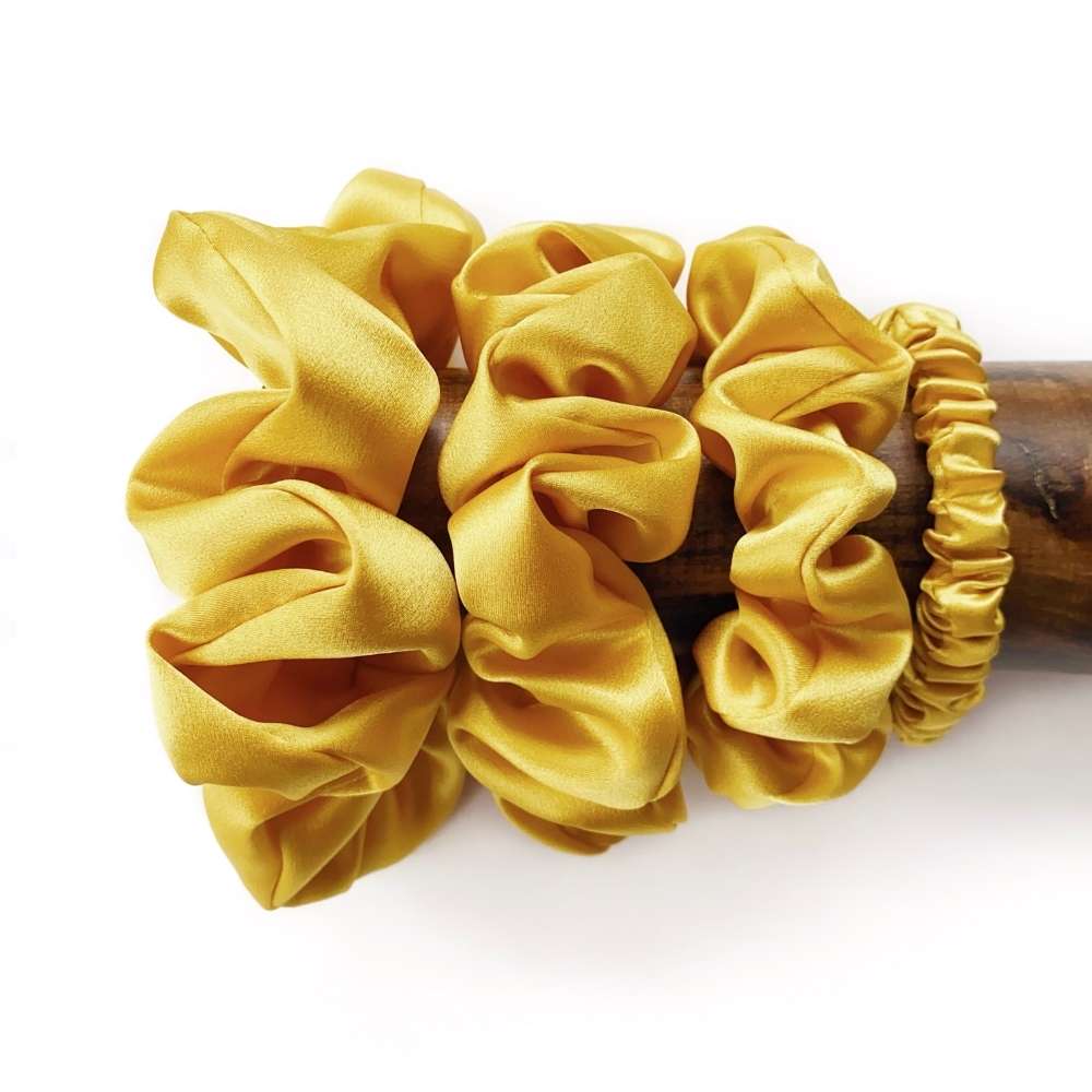 yellow silk scrunchies and hair tie on a wooden block with a white background