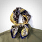 Patterned yellow grey mulberry silk neck scarf draped over a green shirt on a white background